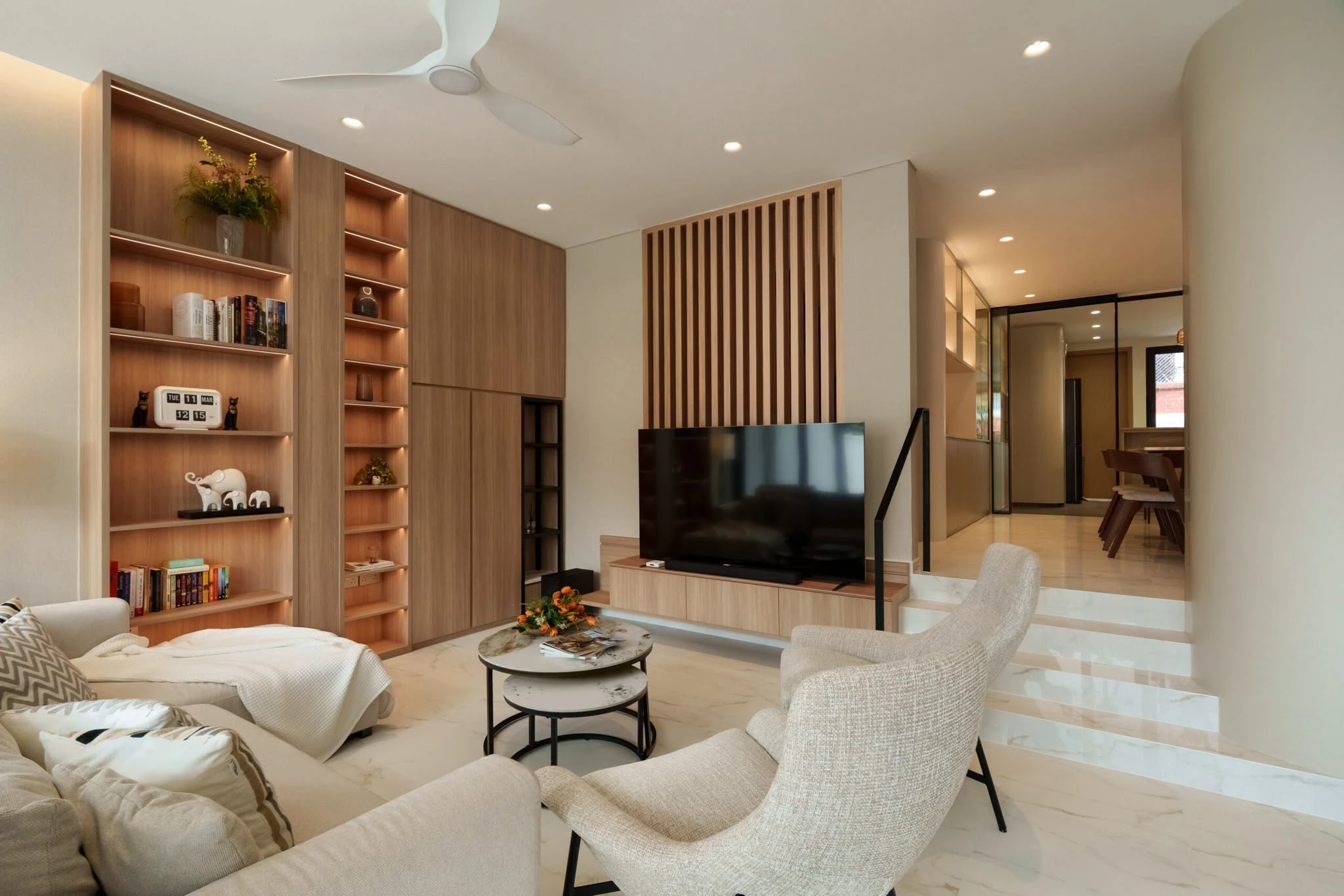 A rich brown living room layout with a custom curved sofa and dark walnut side tables